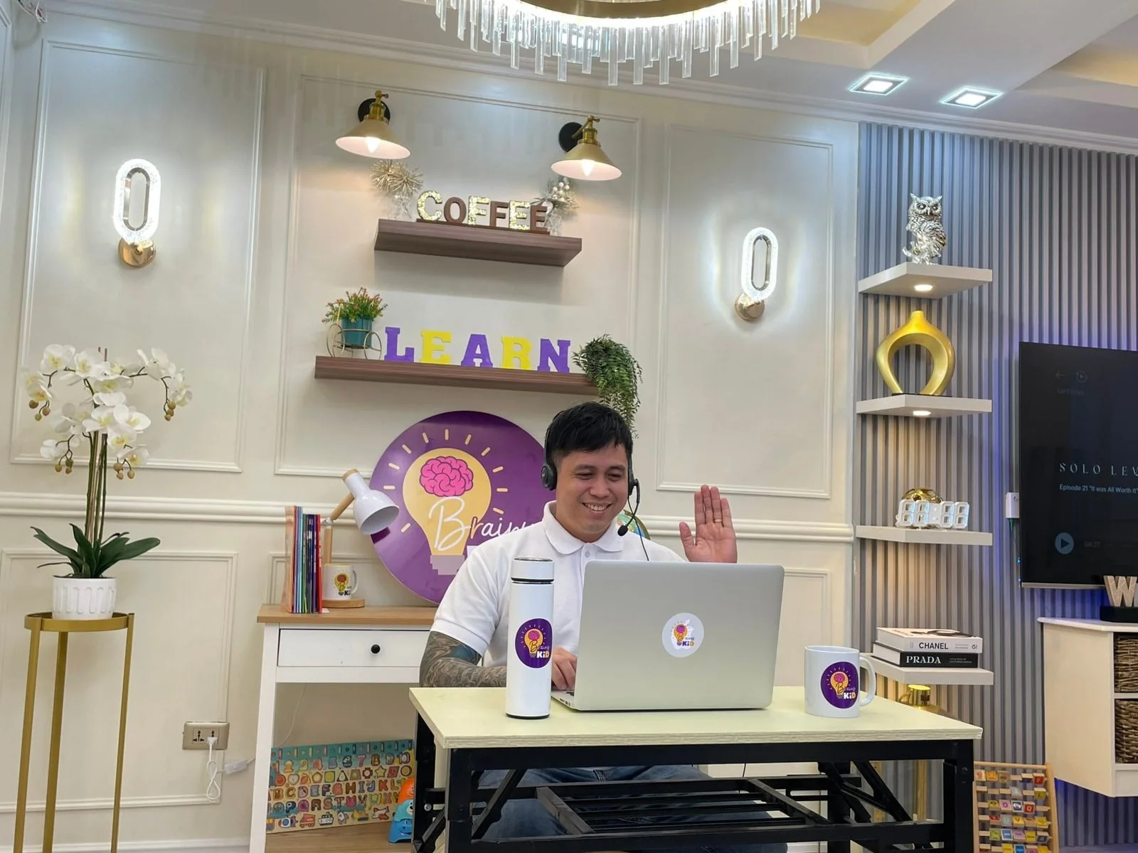 A teacher at a Brainy Kid desk with a laptop and headset